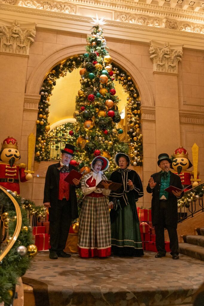 Men and Women in Traditional Clothing Singing by Christmas Tree